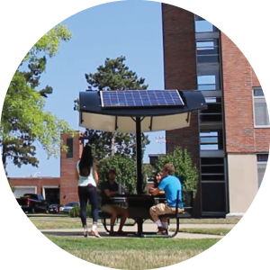 A photo of three students sitting around MSU's student solar table. 