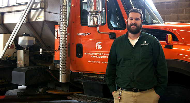 A photo of Landscape Services Operations Supervisor Ross Weaver posing near some snow removal equipment.