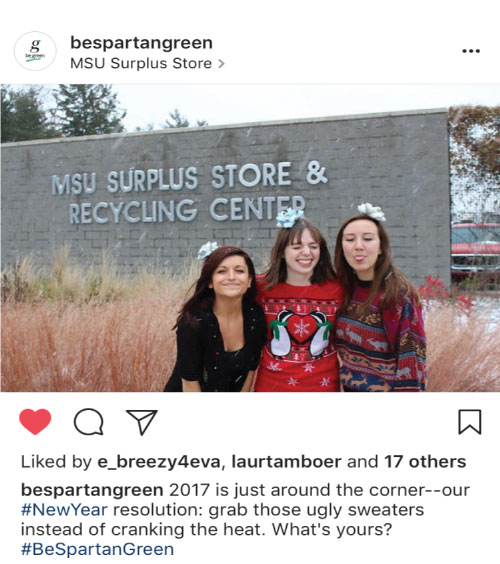 A screenshot of an Instagram post by @BeSpartanGreen, featuring three women posing in Christmas sweaters in front of the MSU Surplus Store. 