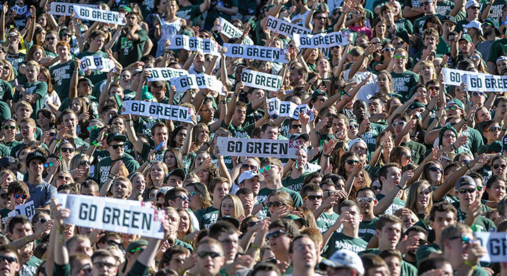 A photo of the Spartan Statdium student section holding up signs that read: Go Green.